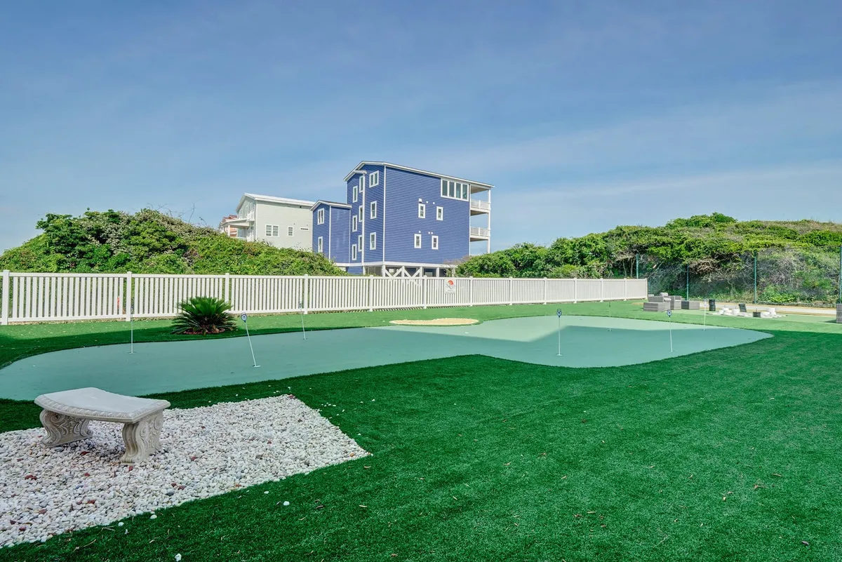A beautiful exterior putting green bordered by lush greenery and a decorative stone bench. The area feels tranquil yet recreational, inviting guests for golf practice or casual gatherings amidst nature.