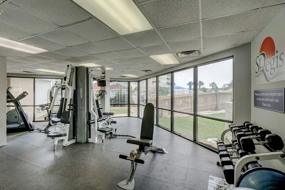 A bright, modern fitness center with exercise machines, weight racks, and large windows offering plenty of natural light. The space is active and motivational, inviting guests to recharge with a workout after work hours.