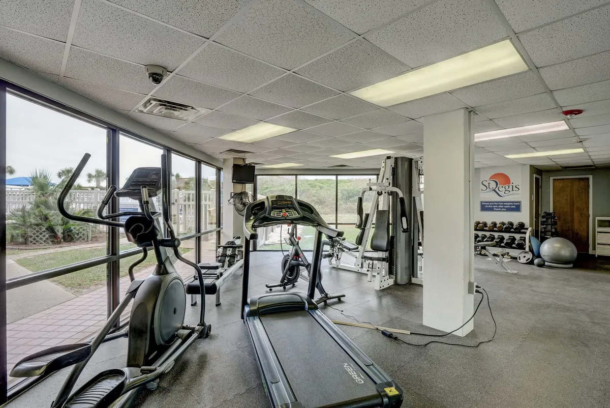 A modern fitness center featuring treadmills, elliptical machines, weight machines, and large windows that let in natural light. The setup encourages users to achieve their fitness goals in an energetic, motivational atmosphere.