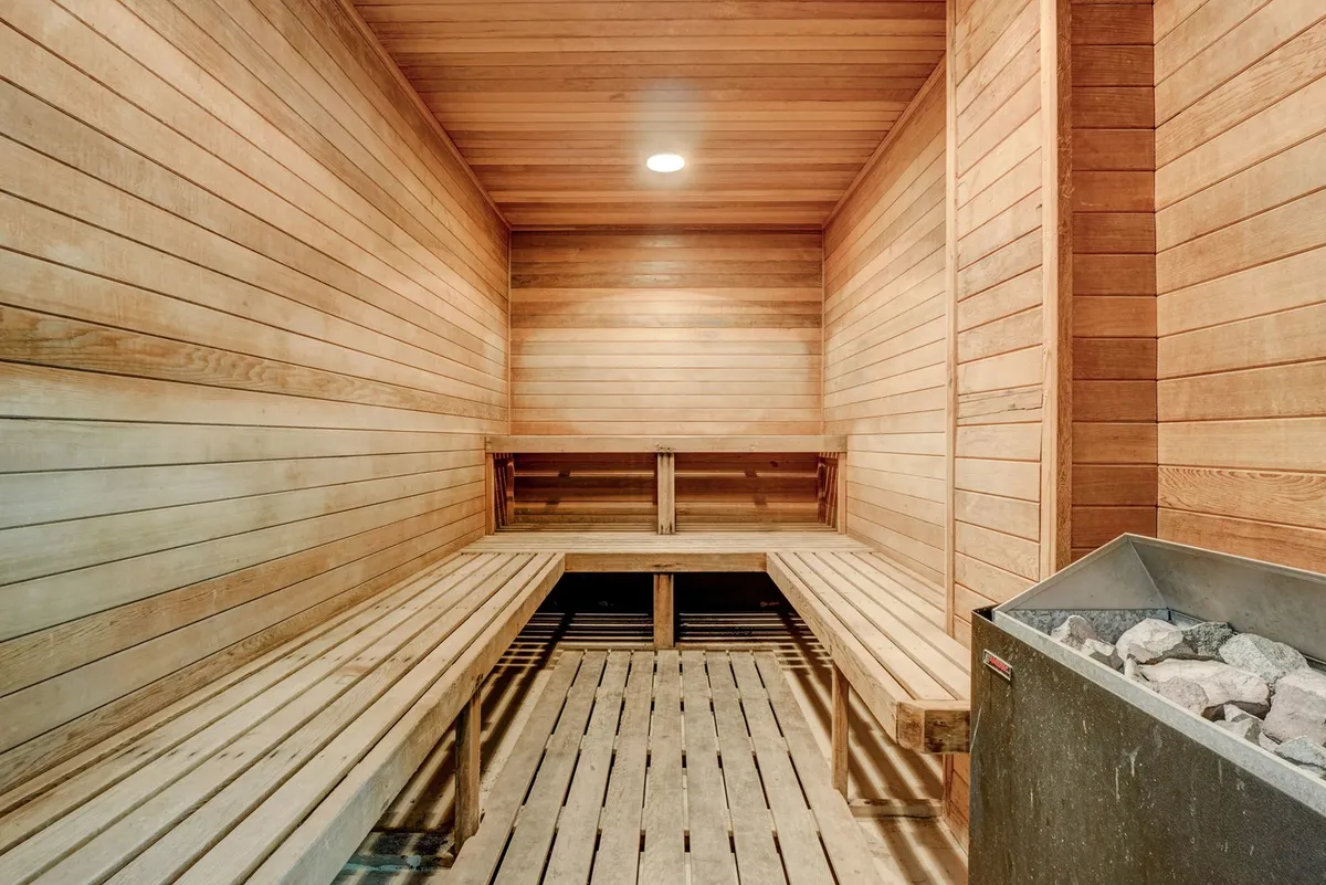 A tranquil, wood-paneled sauna with stone heater and wooden benches invites guests to experience rejuvenation and relaxation. The atmosphere is peaceful, ideal for unwinding after a day by the ocean.