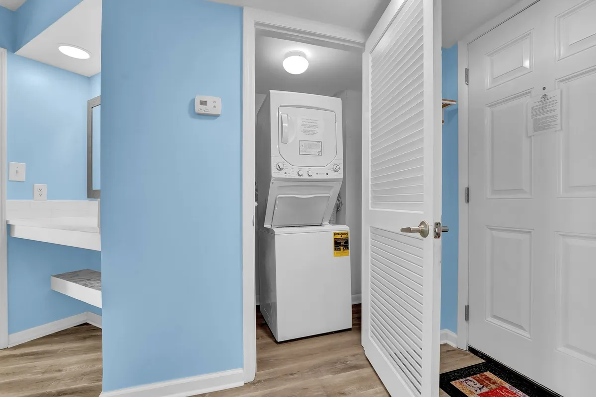A practical laundry area with washer and dryer units set against blue walls, located near an entryway, suggesting ease of access and in-unit convenience.